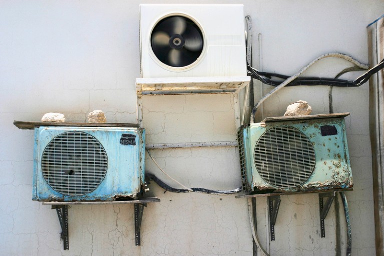 One new and two rusty air conditioning units on the side of a building