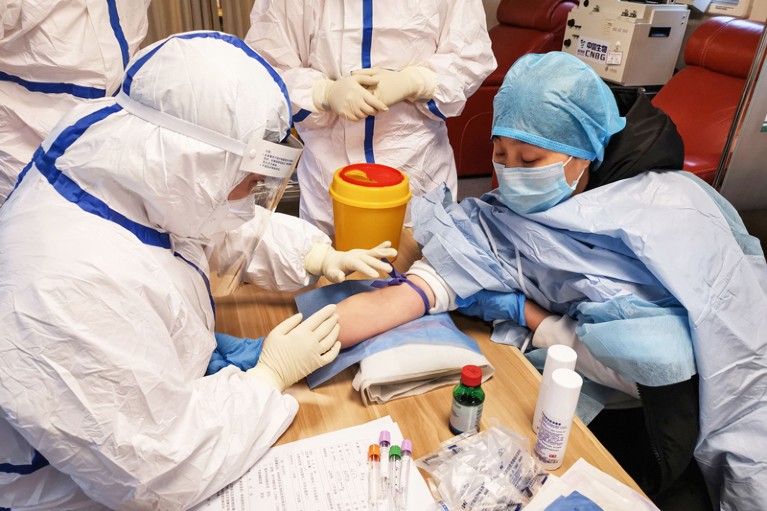 A person donating plasma surrounded by medical workers in protective clothing