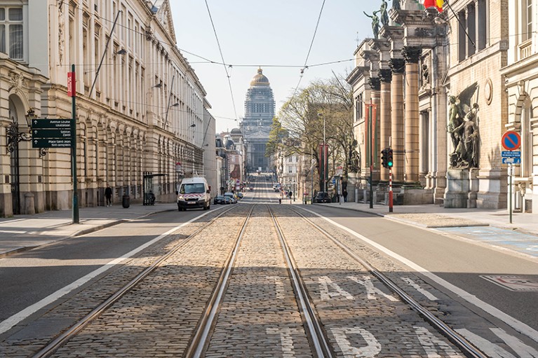 View down a road, featuring tram lines, with a tall building at the end.