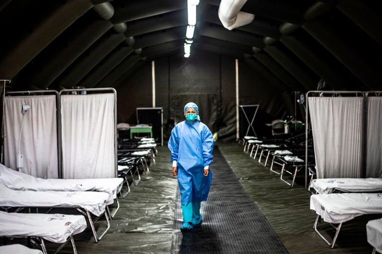 A medical worker in protective clothing and face mask walks through an empty mobile hospital unit in Lima