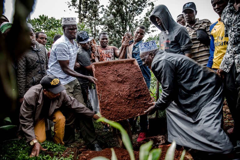 Friends and relatives gather to bury the body of a boy who was allegedly shot by police enforcing curfew in Nairobi