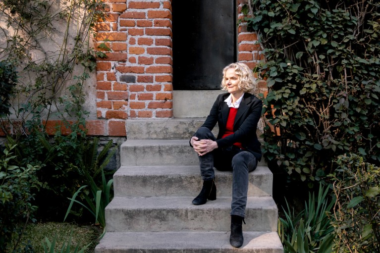 Nora Volkow sits on stones steps in front of a bunker-style door at the Trotsky Museum in Mexico City