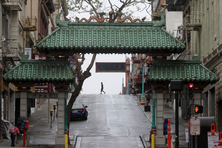 Pedestrian crosses the street behind the Dragon Gate, an entrance to Chinatown in San Francisco