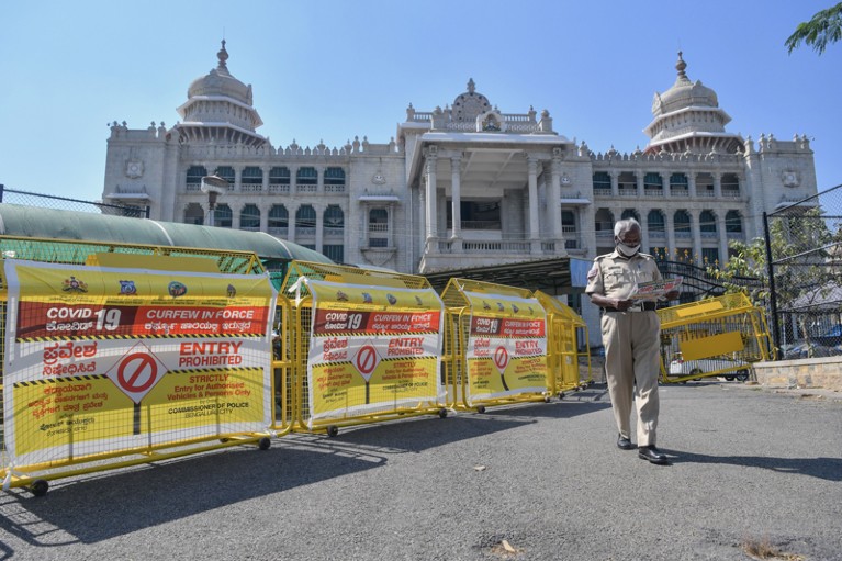 A policeman walks past barricades in front of the Vikasa Soudha building, Bengaluru, India.