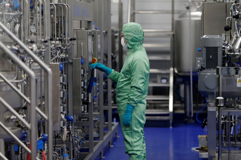 A technician in protective clothing looks at machinery at a vaccine manufacturing facility in China