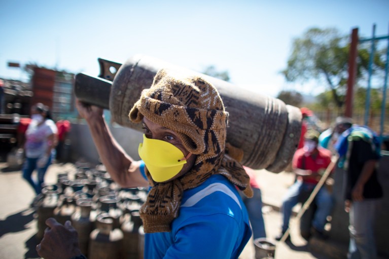 A man wearing a home made face mask carries a butane gas cylinder on his shoulder in Caracas, Venezuela