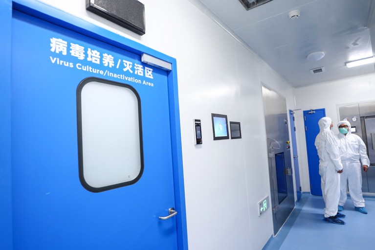 Staff members talk beside the virus culture/inactivation area of a vaccine-production plant in China.