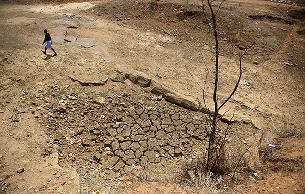 Elevated view of an Indian farmer crossing a dry pond bed.