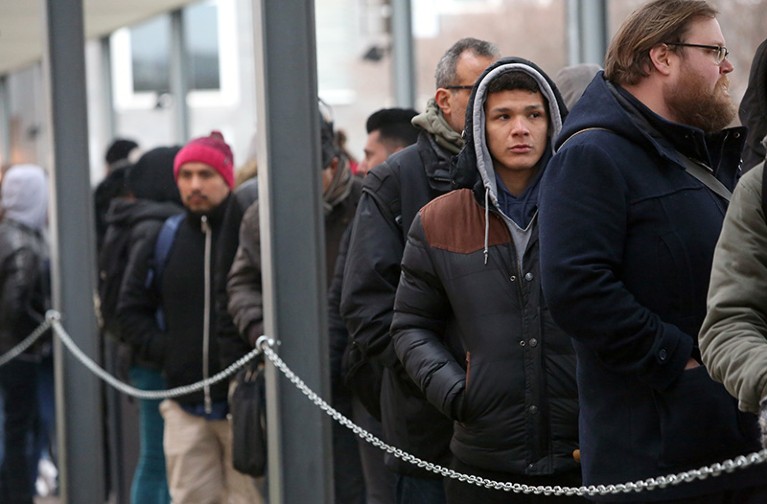 Foreigners wait in line outside the Berlin Immigration Office in Germany