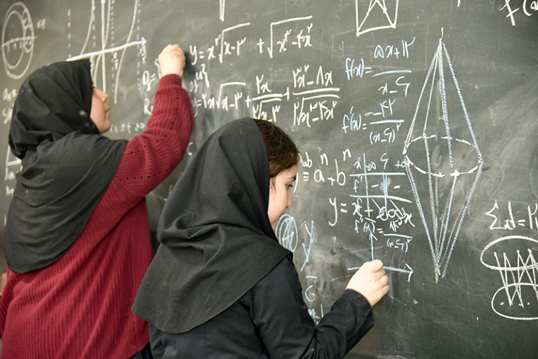 Schoolgirls in Tehran at a blackboard working on maths