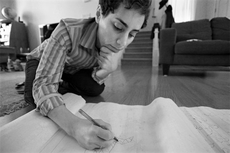 Maryam Mirzakhani writing on paper while on the floor