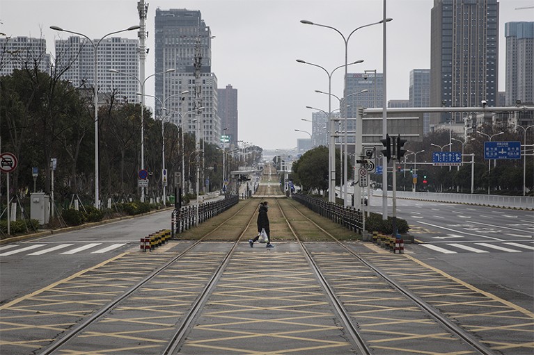 Photo of a person walking across an empty track in Wuhan, China.