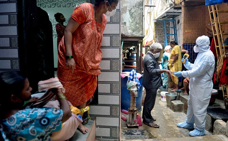 A health-care worker protective gear checks a passer-by's temperature. Women in saris and other Indian dress look on.