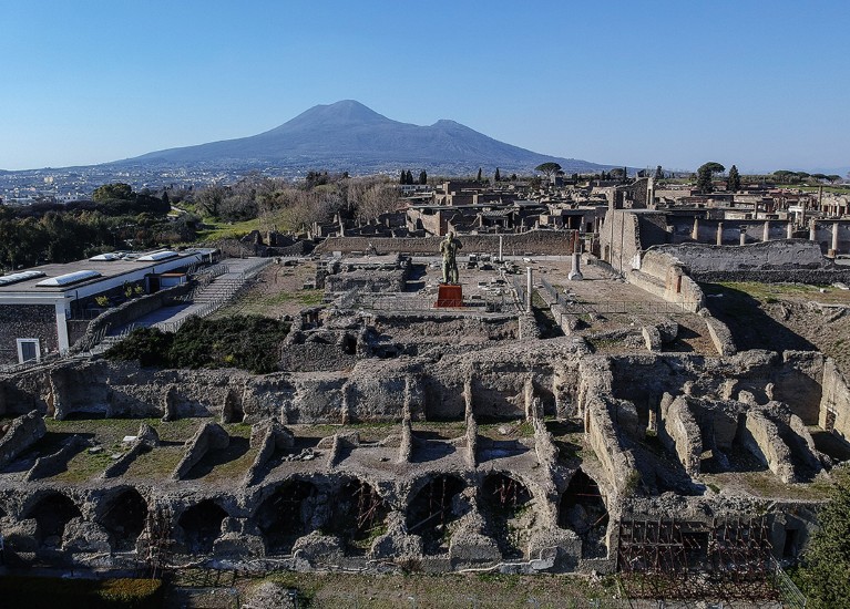 Excavations of ancient ruins in Pompeii, Campania region, Italy, with the volcano Vesuvius in the background.