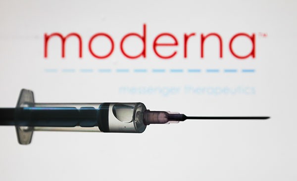 Medical syringe is seen with Moderna company logo