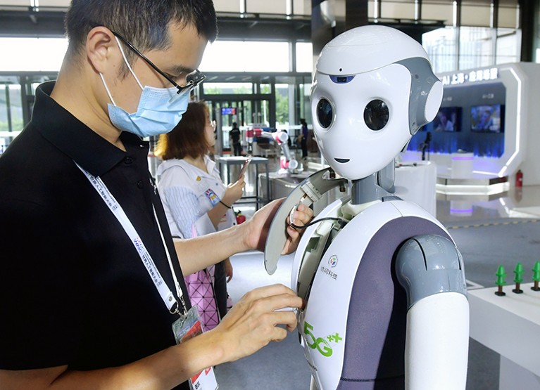 A staff member adjusts a robot at a display.