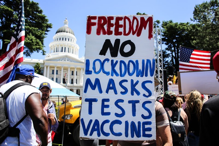 A protester holds a placard that says 'Freedom No Lockdown Masks Tests Vaccine'.