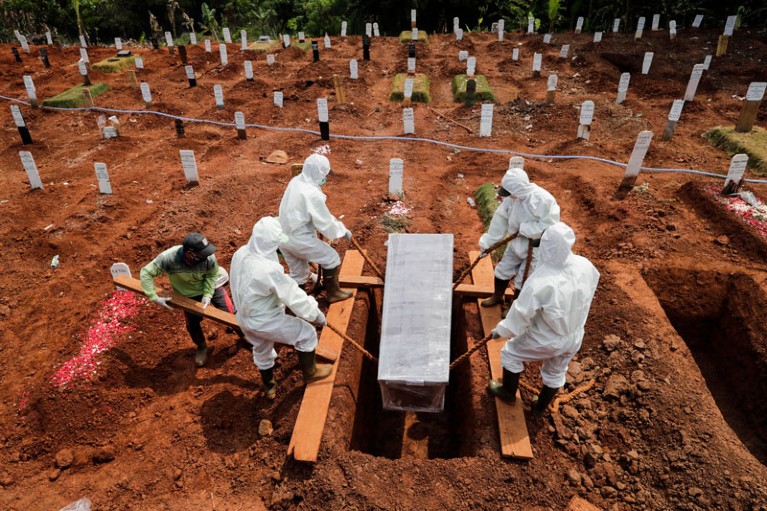Workers clad in hazmat suits bury the coffin of a coronavirus victim