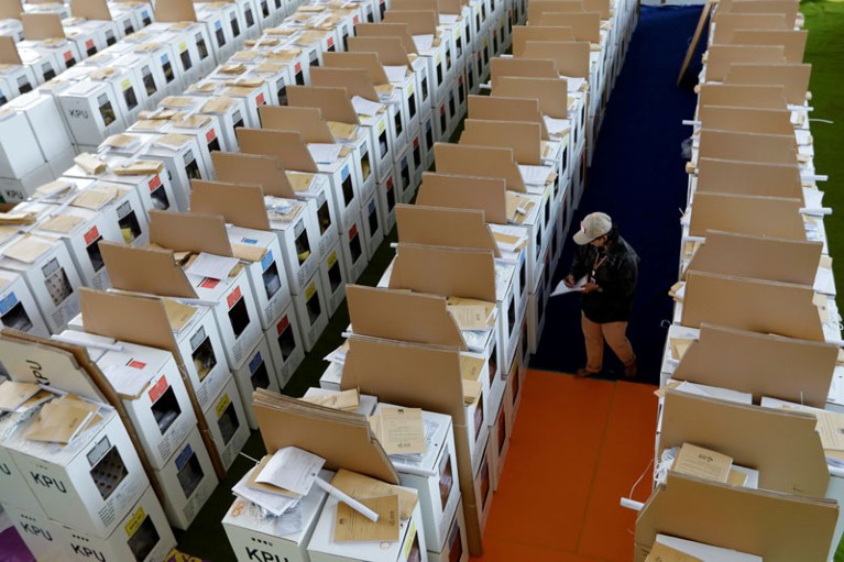 An official supervises ballot boxes for Indonesia's upcoming general election