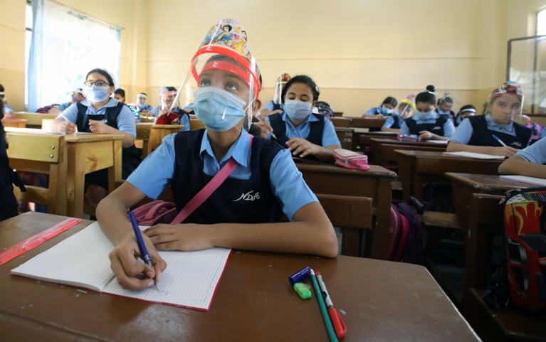 Pupils sitting at desks wearing face masks.