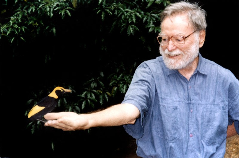 Joseph H. Connell with a yellow and black bower bird perched on his outstretched hand