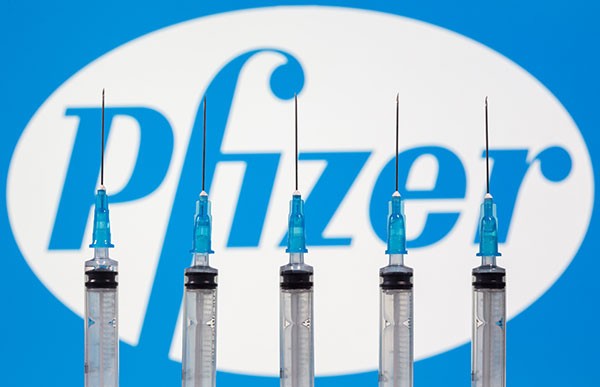 Syringes are seen in front of displayed Biontech and Pfizer logos