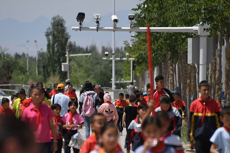 schoolchildren walking below surveillance cameras in China's western Xinjiang region.