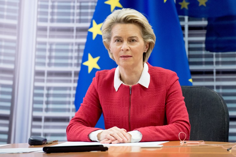 乌苏拉·范德莱恩坐在欧盟旗帜前的桌子前。