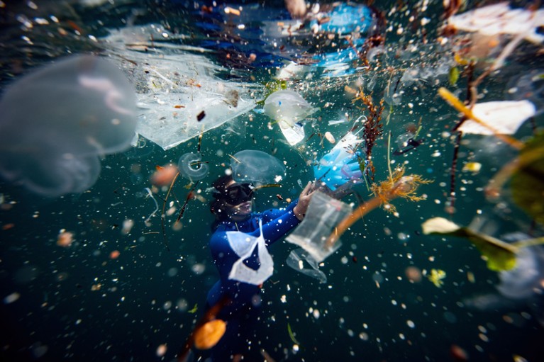 A free-diver dives amid plastic waste