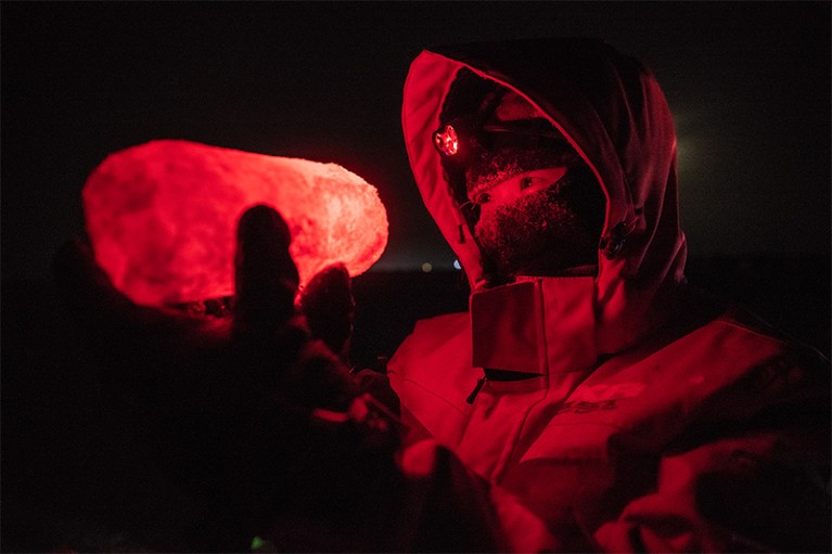 Allison Fong holds an ice core bathed in red light