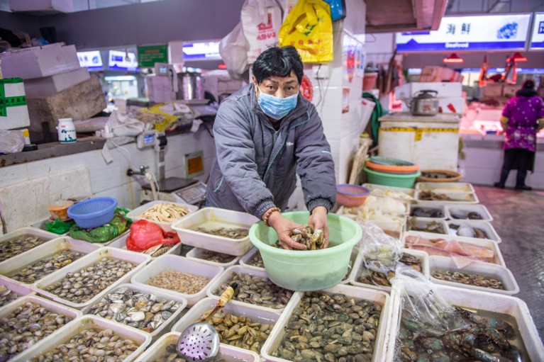 一个戴着面具的存储供应商处理贝类海鲜市场在中国