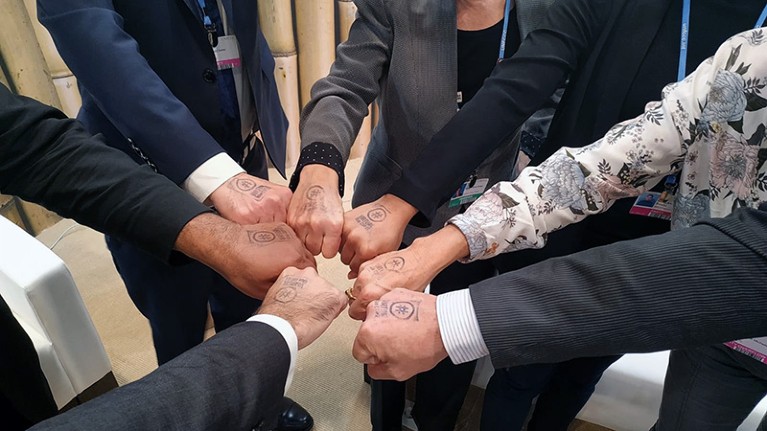 People show their hand stamps in a circle at the VirtualBlueCOP25