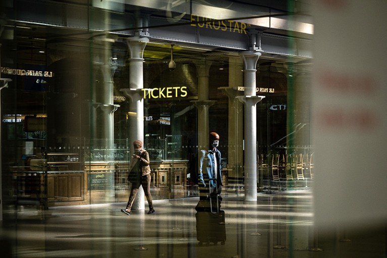 People with luggage and wearing masks walk to the Eurostar train in St Pancras International Station, London