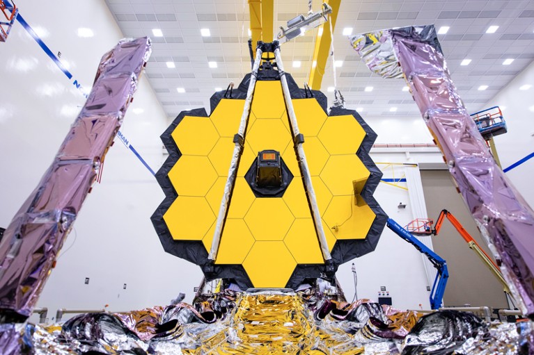 A large yellow mirror made up of many hexagons in a honey comb pattern makes up part of the James Webb telescope