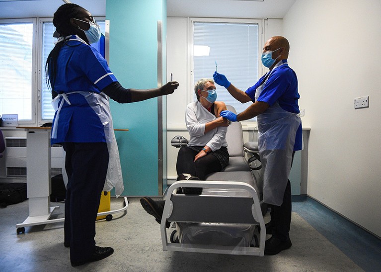 Two medical workers deliver the Novavax trial vaccine to a patient at the Royal Free Hospital in London, UK
