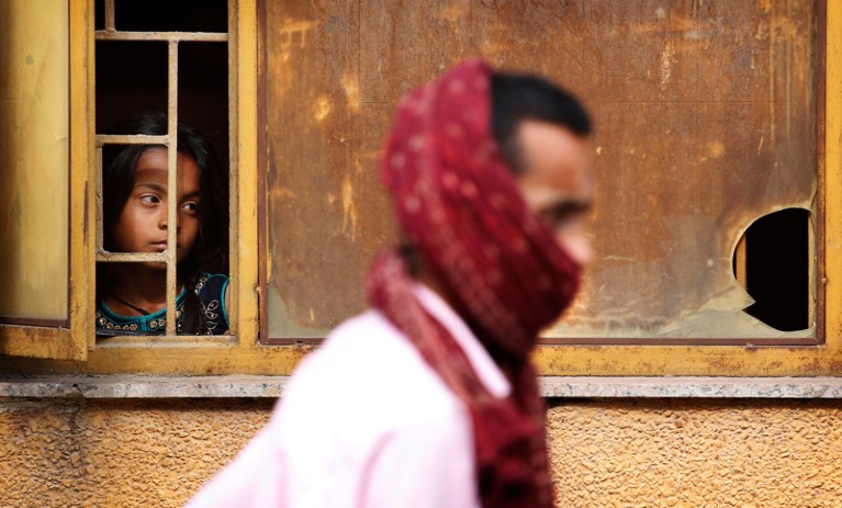 一个年轻的女孩看起来的一个窗口在等待父亲回来在新德里,印度