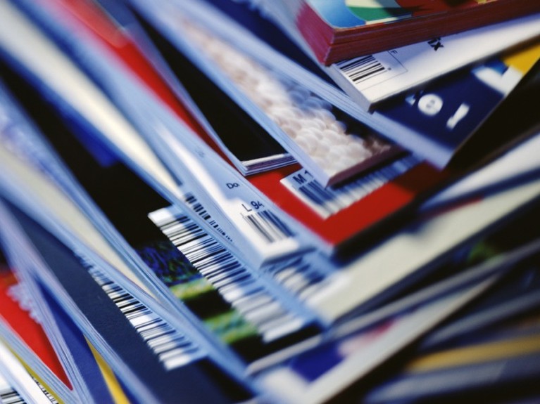 Disorderly stack of magazines, extreme close-up on corners with barcodes.