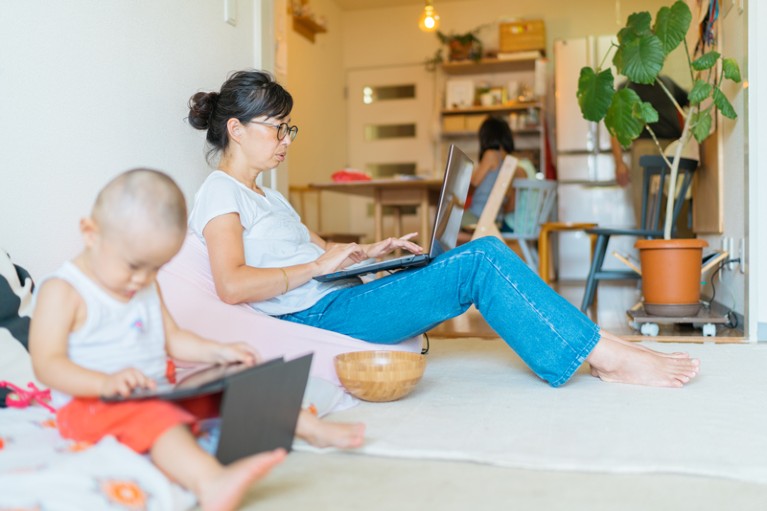 Mother working from home on her laptop with children