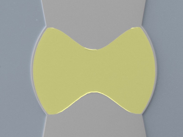 A yellow object in the shape of a bow tie, on a grey background.