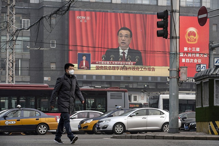 A man walks past a screen showing Chinese premier Li Keqiang speaking at the National People's Congress in Beijing.