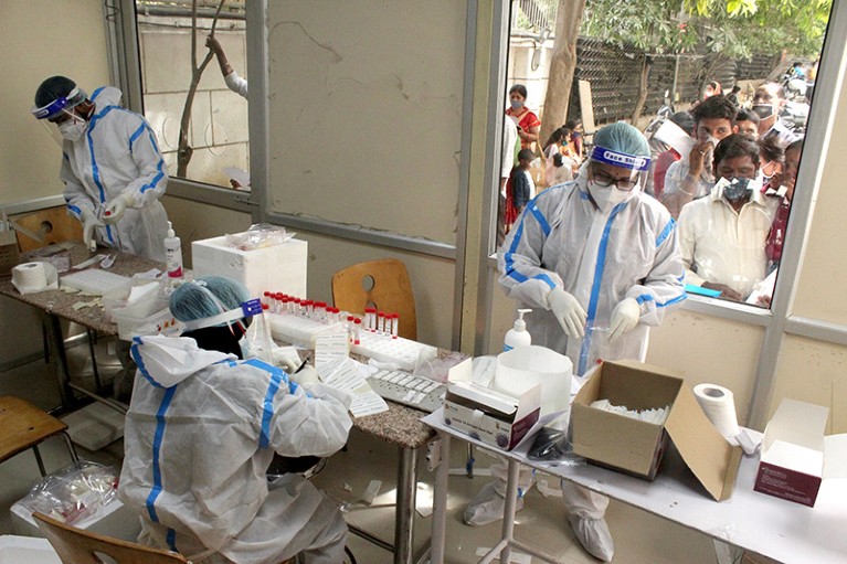 Workers in PPE at a COVID-19 testing booth setup inside the hospital in New Delhi
