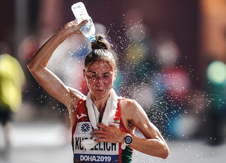 Athlete Sviatlana Kudzelich pours water over her head while running
