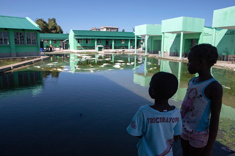 Children look at an elementary school's waterlogged playground in Beira, Mozambique