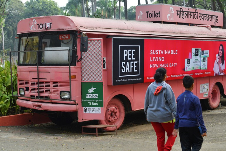 People walking past a pink mobile toilet bus at a public park in Pune