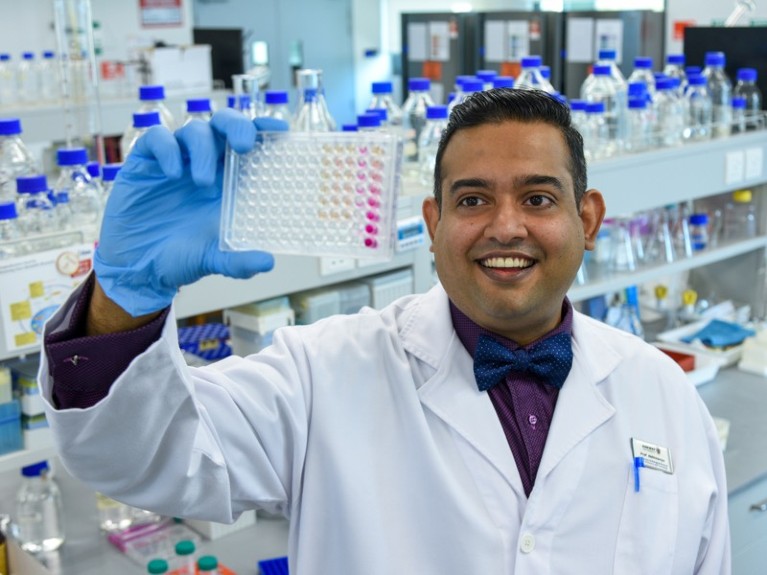 Prof Abhi holding a microplate with biological samples for analysis in his research laboratory.