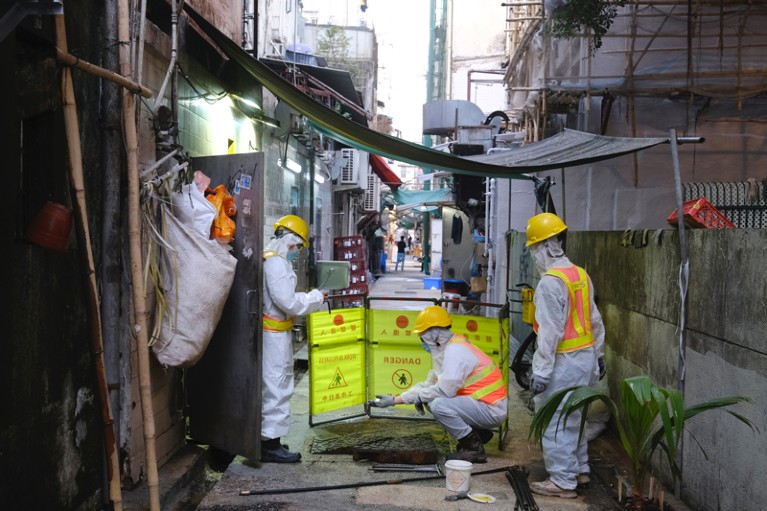 Technicians and government investigators wearing PPE collect samples from a sewage in Hong Kong