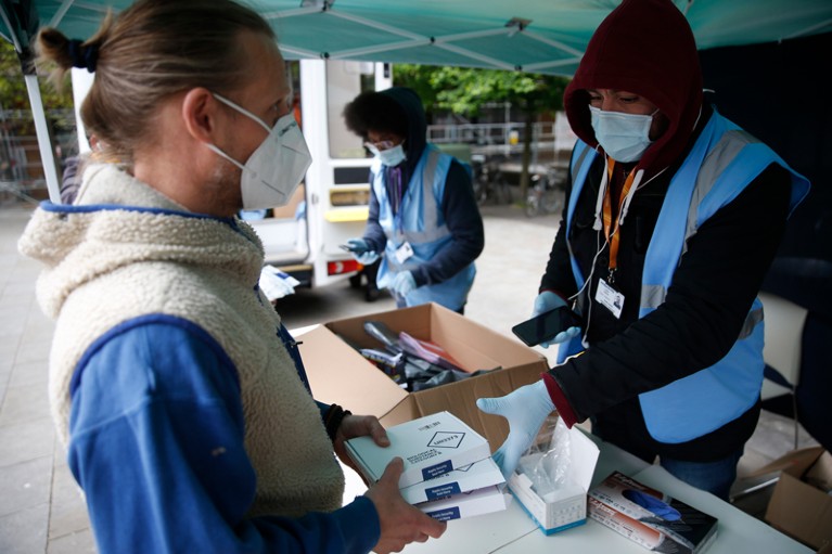 A member of the public returns PCR tests to staff member at a targeted testing site.
