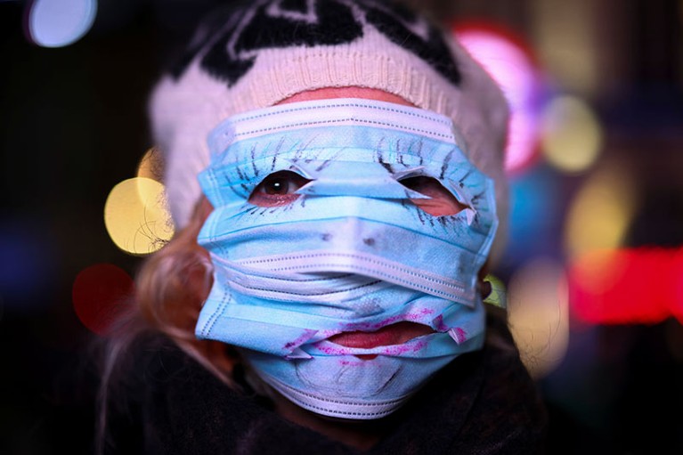 A woman uses protection masks to cover her face during the Million Mask March protest march in London.