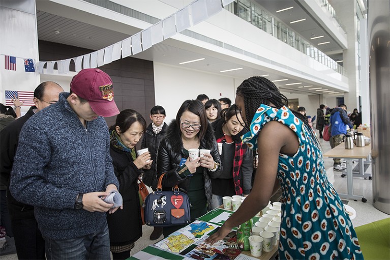Students and visitors gather round a table at the international fair