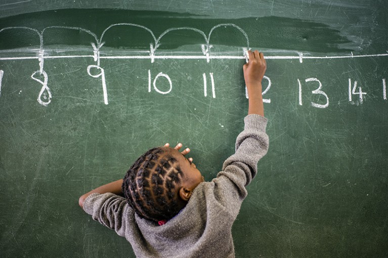 A student counts with the number line on a chalkboard during a maths lesson in Namibia